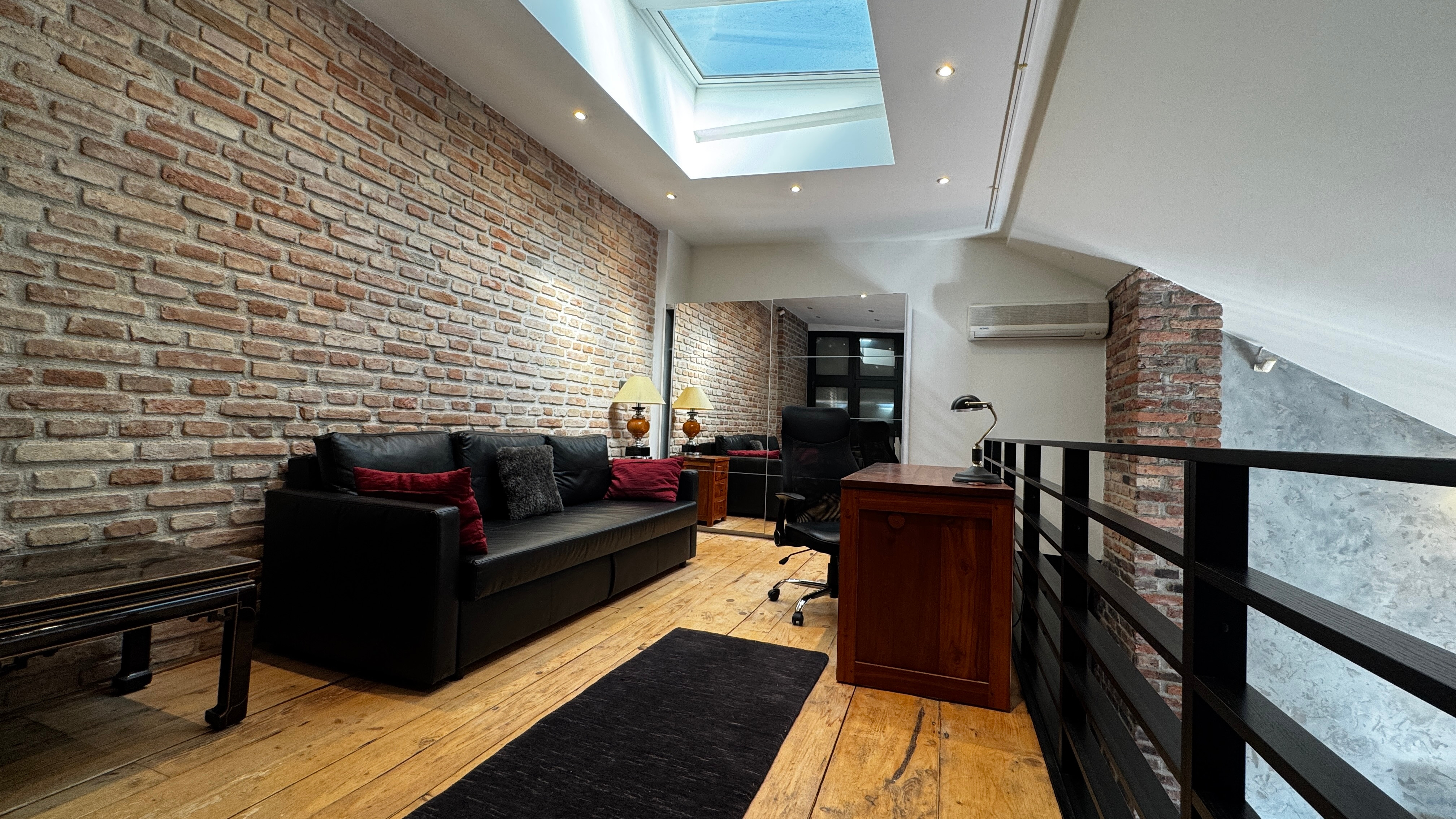 Atelier mezzanine at Polska Penthouse — a gallery-style work studio opening off the upper level of the Great Room, with sofa converting to a double guest bed