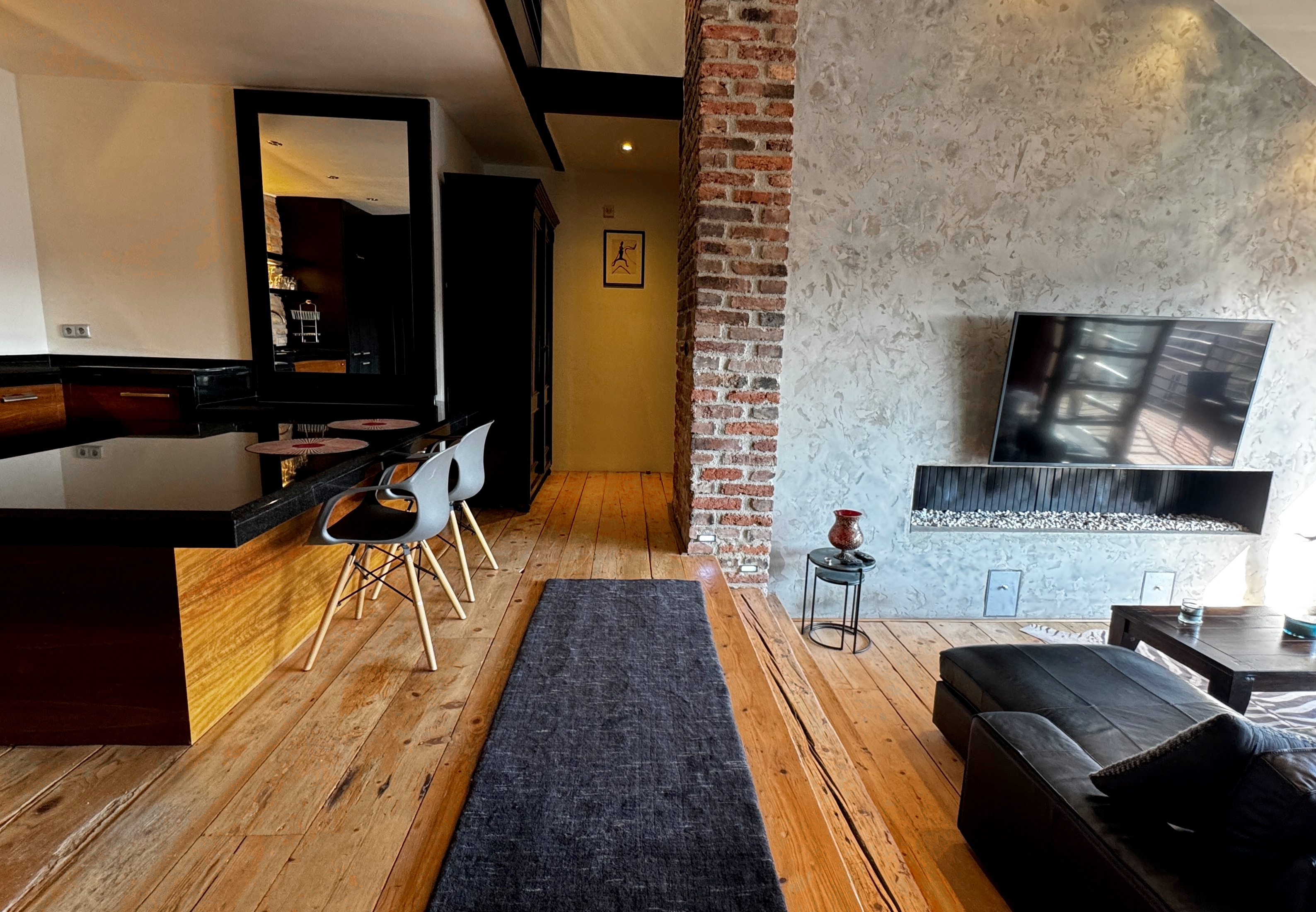 Industrial grand entrance of a Vinohrady triplex penthouse with monumental scale, exposed raw masonry, and solid timber detailing