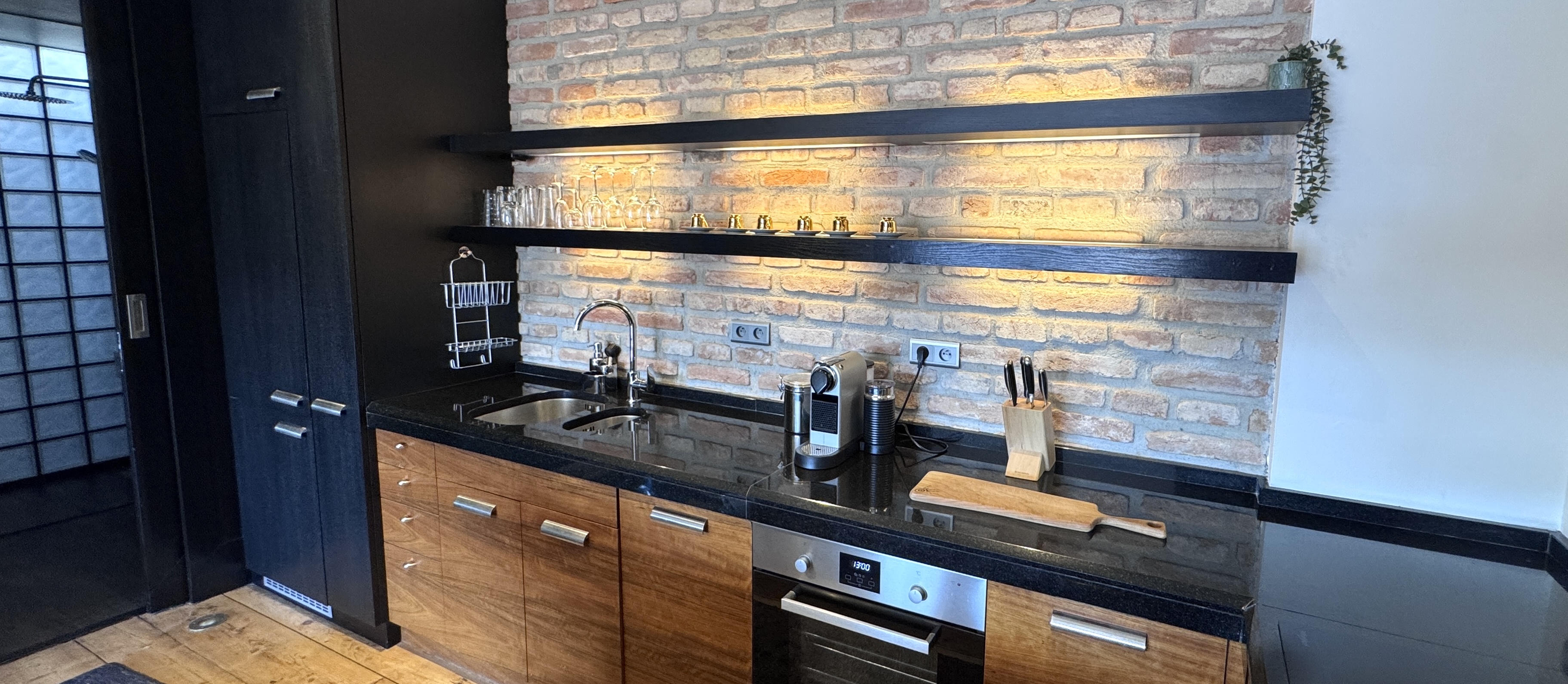The kitchen at Polska Penthouse — seamless black granite worktops and warm under-shelf lighting, connecting the mid-level to The Great Room