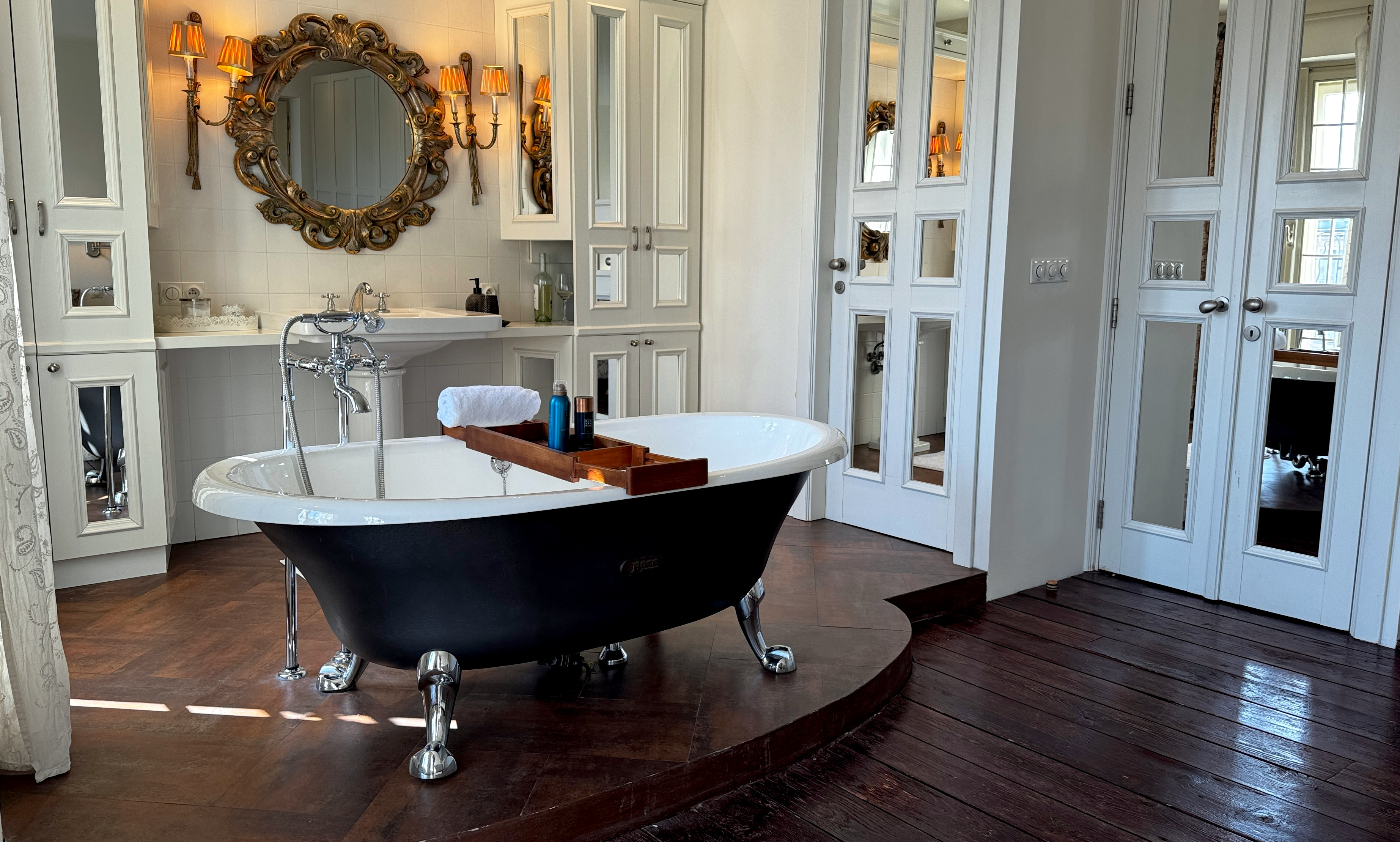 Detail of ROCA freestanding roll-top bathtub on tiled platform in the neoclassical master sanctuary of Polska Penthouse, Prague 2
