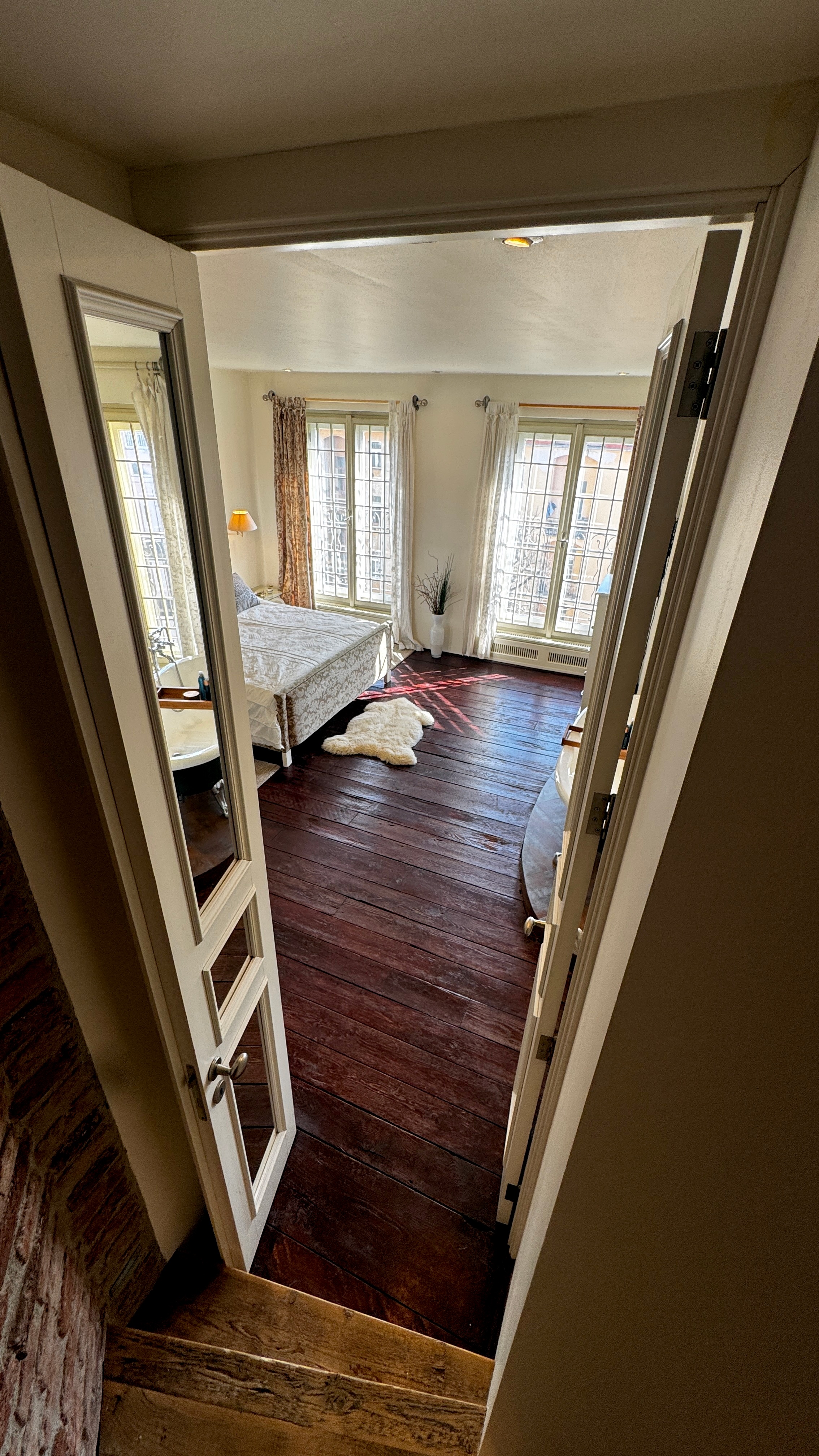 Floor-to-ceiling mirrored double doors marking the entrance to the neoclassical master suite at Polska Penthouse, Prague