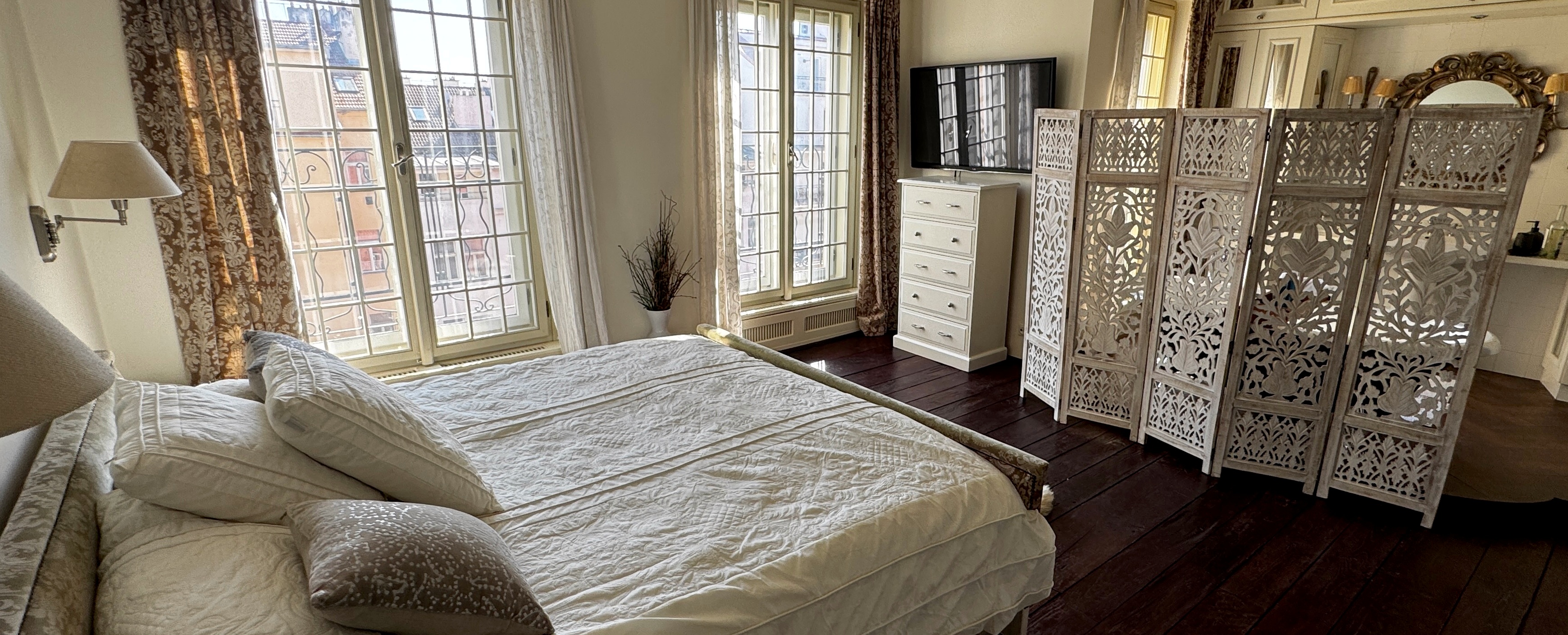 Artisan white carved privacy screen in the master suite of Polska Penthouse — dividing the sleeping area from the open-concept bath