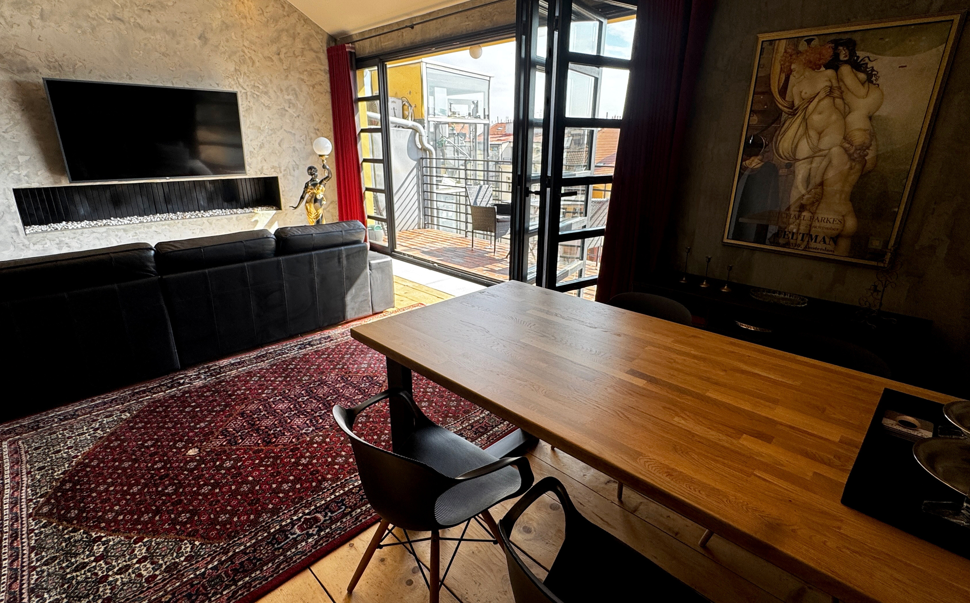 Living and dining area of a Vinohrady penthouse with massive timber flooring transitioning to exposed historic brickwork structural wall