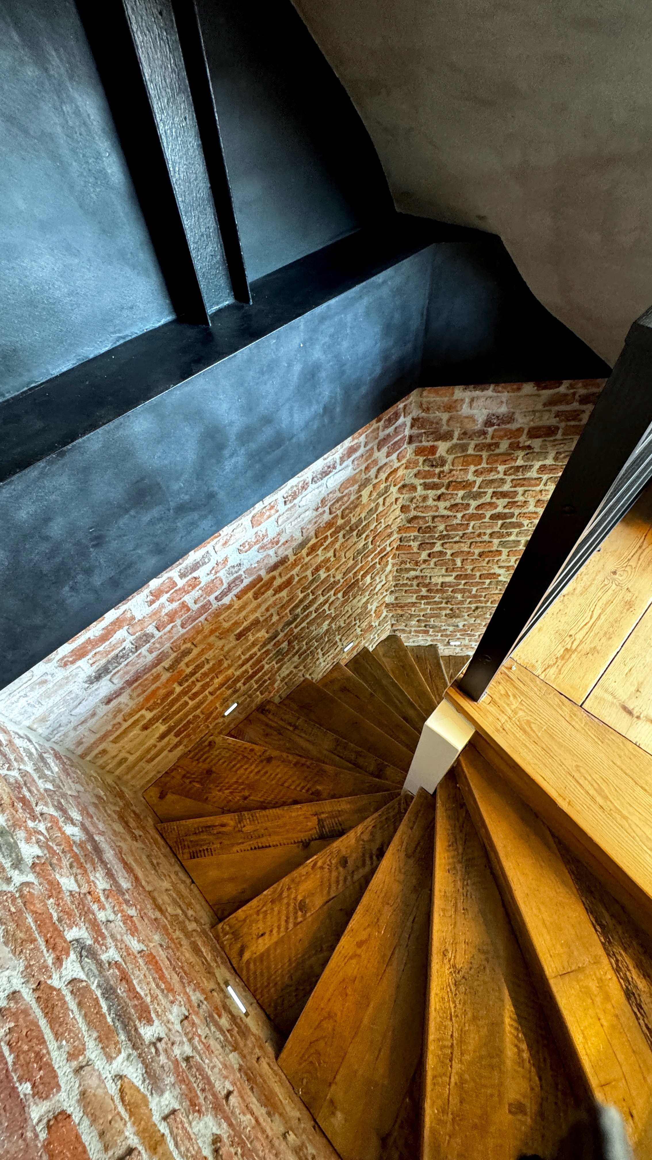 Reclaimed timber staircase descending from the Great Room to the neoclassical master suite in a Vinohrady luxury triplex